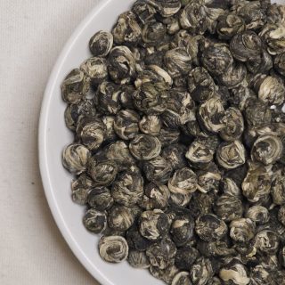 Kuleczki herbaty ręcznie wzijanej Long Zhu na talerzyku.