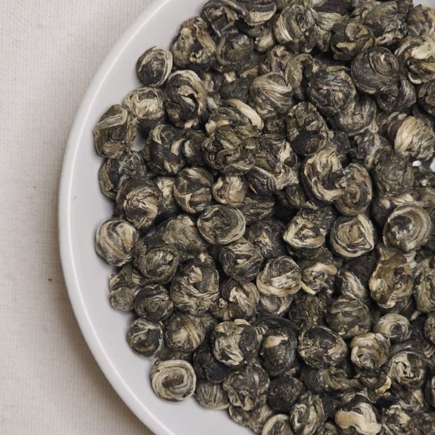 Kuleczki herbaty ręcznie wzijanej Long Zhu na talerzyku.