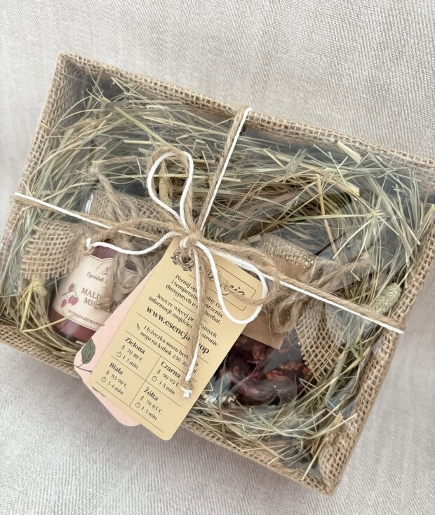 Zestaw prezentowy Malinowa Przyjemność, zapakowany w jutowe pudełko z siankiem, zawierający malinowy miodek i susz owocowy.