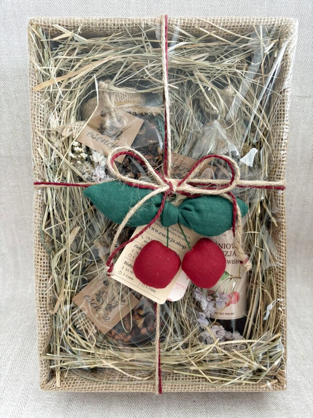 Zestaw prezentowy Wiśniowa Słodycz zapakowany w jutę i celofan, ozdobiony ręcznie szytą zawieszką w kształcie wiśni. W środku syrop wiśniowy, susze owocowe i wiśnie w czekoladzie.