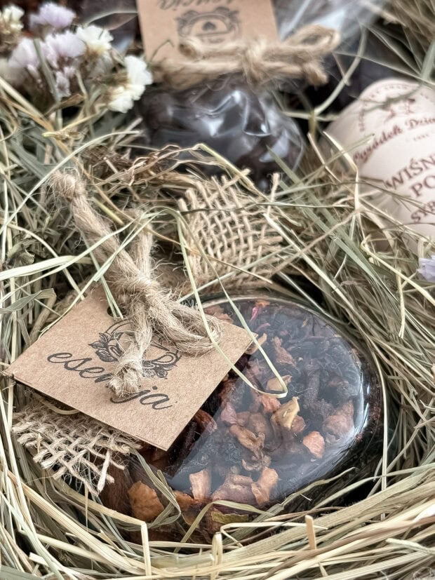 Zbliżenie na produkty w zestawie Wiśniowa Słodycz – syrop wiśniowy, susze owocowe i czekoladowe wiśnie w rustykalnym opakowaniu z juty.