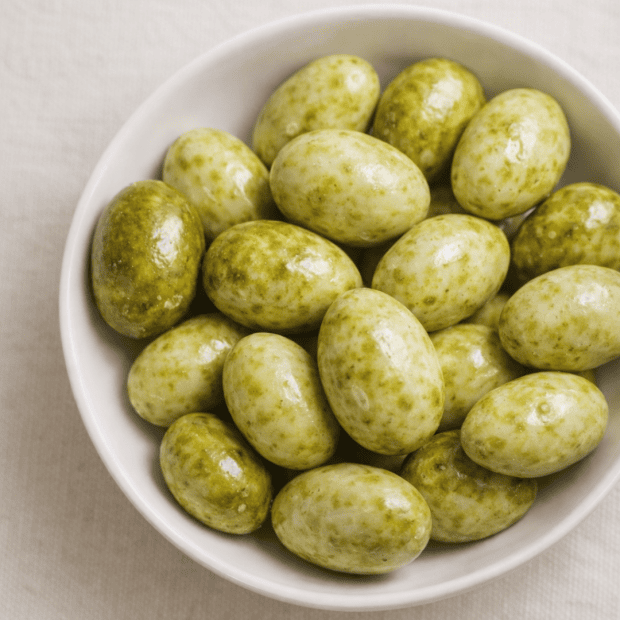 Migdały w białej czekoladzie z zieloną herbatą na talerzyku.