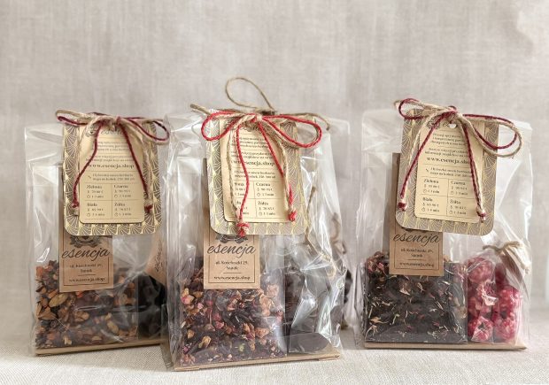 Trzy paczuszki z herbatami i delikatesami, zapakowane ozdobnie z kokardką.