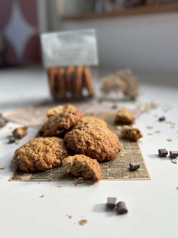 Ciasteczka owsiane rozsypane na stole, w tle paczka ciastek