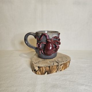 Karmazynowa Ośmiornica na kubku rękodzielniczym.