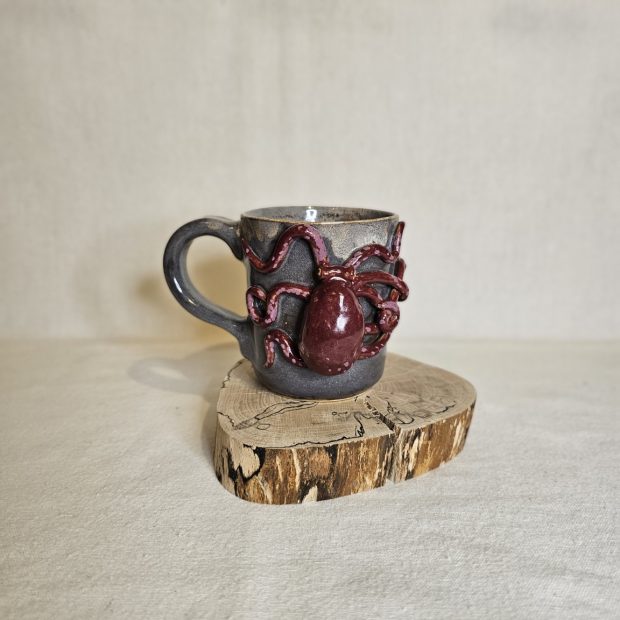 Karmazynowa Ośmiornica na kubku rękodzielniczym.