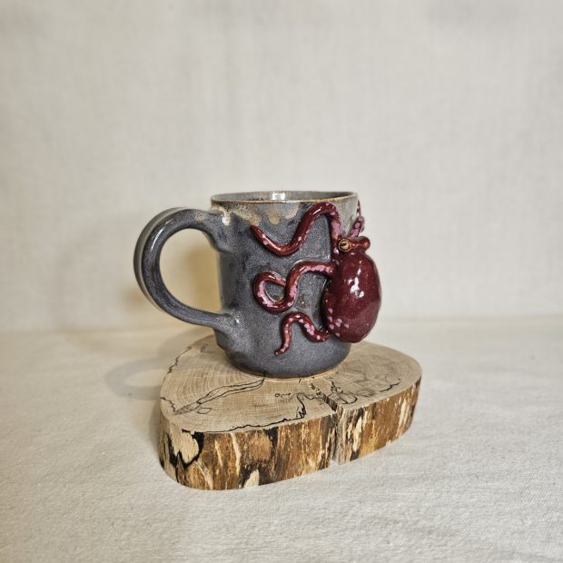 Kubek z karmazynową ośmiornicą z profilu.