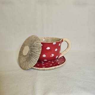 Kubek w kształcie muchomora z opartą pokrywką.