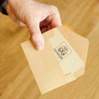 Karta Podarunkowa wystająca z mini koperty, trzymana w dłoni.