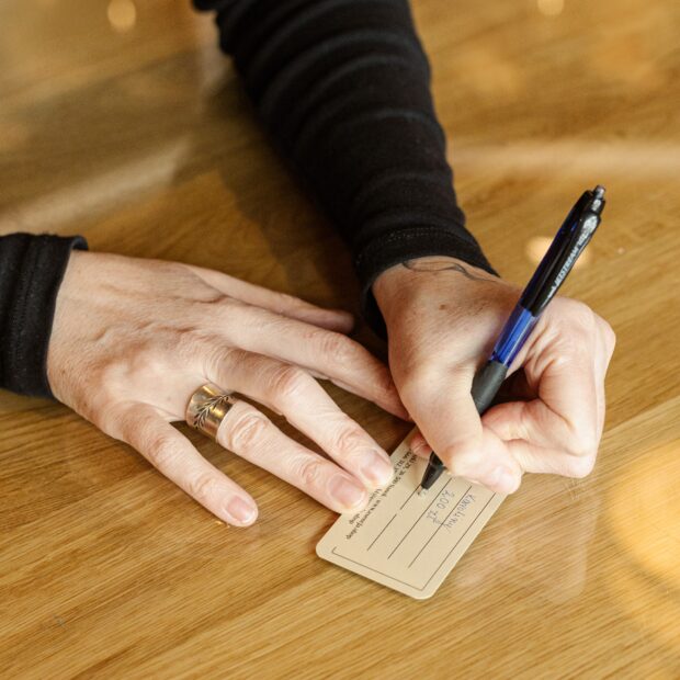 Kobieta wypisuje kartę podarunkową dla klienta.