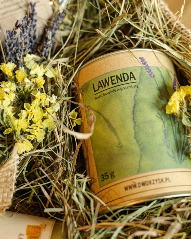 Puszka Lawendy z zestawu prezentowego, otoczona naturalnym siankiem i kwiatami.