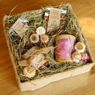 Zestaw prezentowy złożony z herbat, zioł i miodku w pudełku z naturalnymi ozdobami - siankiem i kwiatami.