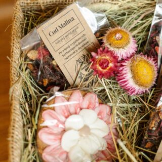 Susz owocowy w transparentnej torebce w towarzystwie pierniczka ręcznie zdobionego, w otoczeniu sianka i kwiatów